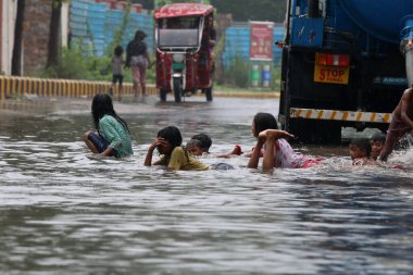 NEW DELHI INDIA 9 Temmuz 2023 Çocuklar 9 Temmuz 2023 tarihinde Yeni Delhi 'de şiddetli muson yağmurlarının ardından Nizamuddin bölgesinde su altında eğlenirken Cumartesi ve Pazar gecelerinde Delhi NCR şiddetli yağmurla ıslandı.