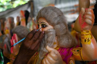 NOIDA INDIA SEPTEMBER 16 2024 An artist adding the finishing touches to the idol of the Hindu god Vishwakarma for the eve of Vishwakarma Puja on September16 ,2024 in Noida, India clipart