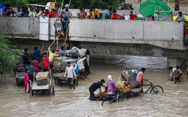 NEW DELHI INDIA 12 Temmuz 2023 Yamuna nehrinin etrafındaki alçak bölgelerden insanlar evleri Mayur Vihar Side yakınlarındaki şiş nehre battıktan sonra daha güvenli bir yere taşınmak için birbirlerine yardım ediyorlar 12 Temmuz 2023 tarihinde Yeni Delhi Hindistan 'da