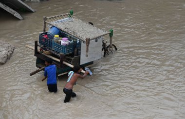 NEW DELHI INDIA 12 HAZİRAN 2023 Yamuna nehri etrafındaki alçak yerlerde yaşayan insanlar, 12 Temmuz 2023 'te Yeni Delhi Hindistan' da Ra tarafından çekildikten sonra evlerinin daha güvenli bir yere taşınması için birbirlerine yardım ediyorlar.