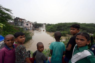 NEW DELHI INDIA JULY 12 2023 Resident carry their belongings from flooded houses as the water level of the Yamuna river rises after being released from Hathni Kund barrage due to heavy rainfall in the Old Garhi Mendu Village on July 12 2023 in New De clipart