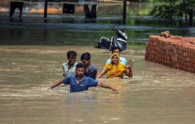 NEW DELHI INDIA 13 HAZİRAN 2023 Yamuna nehri etrafındaki alçak yerlerde yaşayan insanlar, kabaran nehrin taşkın sularından geçerek Mayur Vihar Tarafı yakınlarında daha güvenli bir yere taşınırlar 13 Temmuz 2023 'te Yeni Delhi Hindistan' da Raj K Hindustan Tim tarafından çekilmiştir.