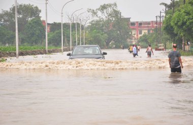 GHAZIABAD INDIA 15 Temmuz 2023 Tronica City ve çevresinde yollar ve lokaller sular altında kaldı ve insanlar daha güvenli yerlere taşınmak ya da 15 Temmuz 'da günlük ihtiyaçlar için ev eşyaları almak için derin sularda yürümeye çalışıyor