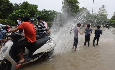 NEW DELHI INDIA 15 HAZİRAN 2023 Shanti Van yakınlarındaki sel suyunda eğlenen insanlar 15 Temmuz 2023 'te Yeni Delhi Hindistan' da akan şiş Yamuna nehri yakınlarındaki bölgeleri sular altında bırakırken nehrin su seviyesi Çarşamba gününden beri yükseliyor.