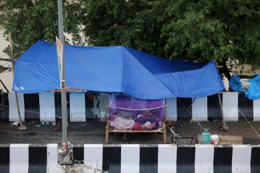 NEW DELHI INDIA 16 HAZİRAN 2023 Sel etkilenen insanlar sabahın erken saatlerinde Mayur Vihar 'ın karşısında 16 Temmuz 2023 tarihinde Yeni Delhi Hindistan' da bir yol kenarı çadırında sivrisinek ağı altında uyuyorlar. Nehrin su seviyesi Çarşamba gününden beri yükseliyor.