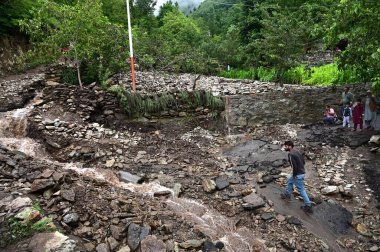 SRINAGAR INDIA JULY 22 2023 People walk across a damaged road following flash floods in Faqir Gujri area on the outskirts of Srinagar on July 22 2023 in Srinagar India Continuous heavy rains have been battering various regions of Jammu and Kashmir re clipart