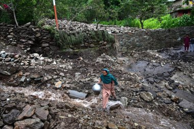 SRINAGAR INDIA JULY 22 2023 A woman crosses a damaged road following flash floods in Faqir Gujri area on the outskirts of Srinagar on July 22 2023 in Srinagar India Continuous heavy rains have been battering various regions of Jammu and Kashmir resul clipart