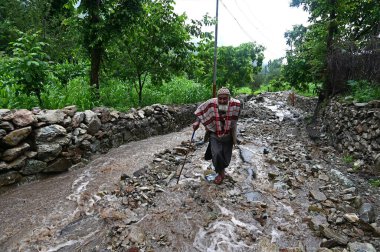 22 Temmuz 2023 'te Srinagar Hindistan' da 22 Temmuz 2023 'te Srinagar Mahallesi' ndeki Faqir Gujri bölgesinde meydana gelen ani sel baskınlarının ardından hasarlı bir tepe yolunda yürüyen bir adam, Jammu ve K 'nin çeşitli bölgelerine şiddetli yağmurlar yağdı.