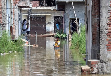 GREATER NOIDA INDIA 24 HAZİRAN 24 HAZİRAN 2023 Hindon nehri etrafındaki alçak yerlerde yaşayan insanlar, kabaran nehrin taşkın sularından geçerek Purana Haibatpur köyünde 24 Haziran 2023 'te Büyük Noida Hindistan' da Sunil Gh tarafından çekilmiştir.