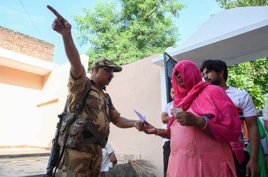 GURUGRAM INDIA OCTOBER 5 2024 CISF personnel check the id of voter before cast their vote for Haryana Assembly Election at Shiv Public School Sohna on October 5 2024 in Gurugram India A total of 1 031 candidates are contesting in all 90 assembly cons clipart