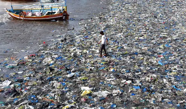 MUMBAI INDIA 5 Haziran 2023 Bir çocuk 5 Haziran 2023 'te Mumbai' de Dünya Çevre Günü Colaba 'da Badhwar Park yakınlarında tonlarca plastik atık arasında yürür. 