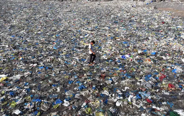 MUMBAI INDIA 5 Haziran 2023 Bir çocuk 5 Haziran 2023 'te Mumbai' de Dünya Çevre Günü Colaba 'da Badhwar Park yakınlarında tonlarca plastik atık arasında yürür. 