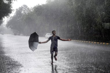 NEW DELHI INDIA JUNE 16 2023 A boy enjoying amid heavy rain at Bhagwan Dass road near Mandi House on June 16 2023 in New Delhi India The India Meteorological Department had predicted light rain with gusty winds in Delhi NCR on Thursday According to t clipart