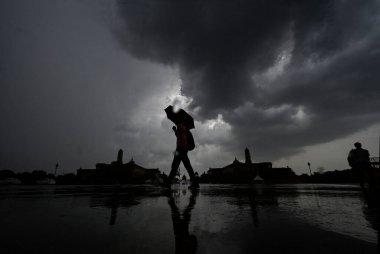 YENİ DELHI INDIA 16 HAZİRAN 2023 Bir adam, yağmurlu bir günde Vijay Chowk 'un üzerinde kara bulutların altında yürür Yeni Delhi' de 16 Haziran 2023 Hindistan Meteoroloji Bölümü, Perşembe günü Delhi NCR 'de şiddetli rüzgarlarla hafif yağmur öngörmüştü.