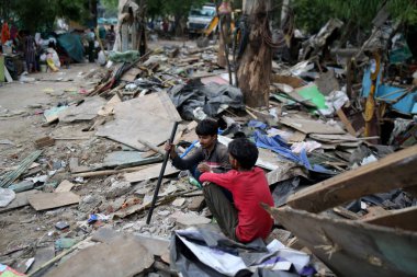 NEW DELHI INDIA HAZİRAN 12023 KİŞİ, Pragati Meydan yakınlarında PWD tarafından Yeni Delhi 'deki Bhairon Marg' da yürütülen bir saldırı girişimi sonrası yıkılmış derme çatma araçlarının yanında insanlar görüldü.