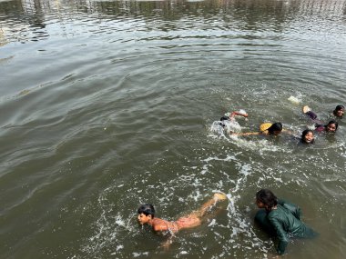 NEW DELHI INDIA JUNE 12 2023 Childrens enjoy at Agra drain river on harsh sunny day during heat waves near Kalindi Kunj on June 12 2023 in New Delhi India India is witnessing heatwaves in various parts of the country in recent days Photo by Salman Al clipart