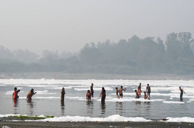 NOIDA INDIA NOVEMBER 5. 2024 Dindarlar, Chhas Puja 'nın 5 Kasım 2024 tarihinde Noida Hindistan' daki ilk gününde kirli Yamuna Nehri 'nde Puja' yı sahneleyecekler.