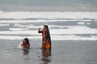 NOIDA INDIA NOVEMBER 5. 2024 Dindarlar, Chhas Puja 'nın 5 Kasım 2024 tarihinde Noida Hindistan' daki ilk gününde kirli Yamuna Nehri 'nde Puja' yı sahneleyecekler.