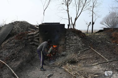SRINAGAR INDIA 2 Aralık 2024 Bir işçi 2 Aralık 2024 'te Ganderbal ilçesindeki bir köyün kazanına hasır döker Srinagar Hindistan Wicker' dan yaklaşık 20 kilometre uzaklıkta sepet mobilya ve yangın kapları yapmak için kullanılır. 
