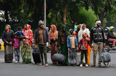 NEW DELHI, INDIA - 8 Aralık 2024 'te, Hindistan' ın Yeni Delhi kentinde, yolun karşısına geçmek için bekleyen banliyö sakinleri sabah soğuğuna ve sise karşı cesurca göğüs gerdiler. Delhi 'nin asgari sıcaklığı 7C civarında seyrediyor. 