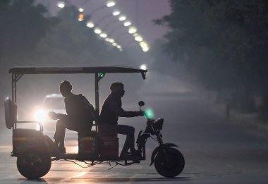 NOIDA, INDIA - 8 Aralık 2024 Noida, Hindistan 'da soğuk ve hafif sisli bir sabah, sıcak giysiler içinde banliyö dışarı çıktı. Delhi 'nin asgari sıcaklığı 7C civarında seyrediyor. 