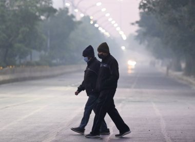 NOIDA, INDIA - 8 Aralık 2024 Noida, Hindistan 'da soğuk ve hafif sisli bir sabah, sıcak giysiler içinde banliyö dışarı çıktı. Delhi 'nin asgari sıcaklığı 7C civarında seyrediyor. 