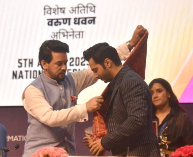 NEW DELHI INDIA APRIL 5 2023 Union Minister Ministry of Information and Broadcasting Anurag Thakur with Varun Dhawan Actor during the an agreement signing event between the Ministry of I and B and Amazon at National Media Centre on April 5 2023 in Ne clipart