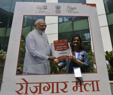 NEW DELHI INDIA APRIL 13 2023 Newly inducted appointee poses for a photo with a cutout of Prime Minister Narendra Modi at the Rozgar Mela at National Media Centre on April 13 2023 in New Delhi India The Rozgar Mela is a step towards the fulfillment o clipart