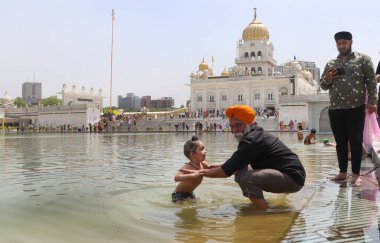 YENİ DELHI INDIA APRIL 14 YIL 2023 Dindar Gurudwara Bangla Sahib 'in kutsal göletine 14 Nisan 2023' te Vaisakhi festivali vesilesiyle daldı.