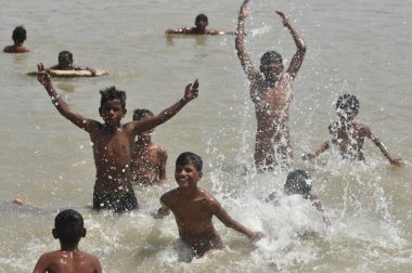 NEW DELHI INDIA 15 Nisan 2023 Çocuklar 15 Nisan 2023 tarihinde Yeni Delhi Indi 'de en yüksek sıcaklığın 40 dereceye ulaştığı Kuzey Hindistan' da sıcak hava dalgası koşullarının hakim olduğu su göletinin içinde keyfini çıkarıyorlar.