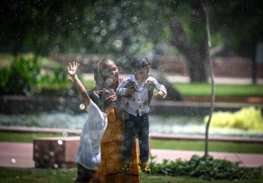 NEW DELHI INDIA 18 Nisan 2023 Bir aile Hindistan 'da 18 Nisan 2023' te Delhi NCR 'de sıcaklık yükselirken Hindistan kapısında sıcak bir günde su püskürtücülerinden çıkan su jetlerinin keyfini çıkarır. 