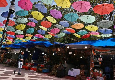 NEW DELHI INDIA APRIL 18 2023 Visitors walks under the Umbrella Roof at Dilli Haat which give some relief from rising temperature on April 18 2023 in New Delhi India Delhi registered a maximum temperature of 40 4 degrees Celsius four notches higher t clipart