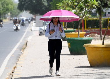 NOIDA INDIA APRIL 18 2023 Commuters under the umbrella out in the hot summer day at sector 21 on April 18 2023 in Noida India Delhi registered a maximum temperature of 40 4 degrees Celsius four notches higher than normal the fourth consecutive day th clipart