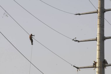 GURUGRAM INDIA APRIL 23 2023 Dakshin Haryana Bijli Vitran Nigam DHBVN workers seen changing the High Tension wires before the summer season on a newly installed high tension electric pole at sector 15 near Roseland Park on April 23 2023 in Gurugram I clipart