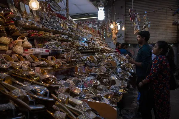 MUMBAI INDIA NİSAN 20 Nisan 2023 Müslüman kadın, 20 Nisan 2023 'te Hindistan' da Modh Ali Rd 'de yapılacak olan Müslüman bayram alışverişi kapsamında bir tezgahtaki ayakkabılara bakıyor. 