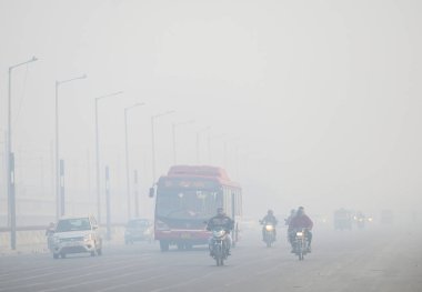 NEW DELHI INDIA DECEMBER 17 2024 Commuters step out in foggy winter cold morning amid rising air pollution near kalindi kunj on December 17 2024 in New Delhi India Delhi NCR witnessed severe smog and drastically reduced visibility on morning as air q clipart