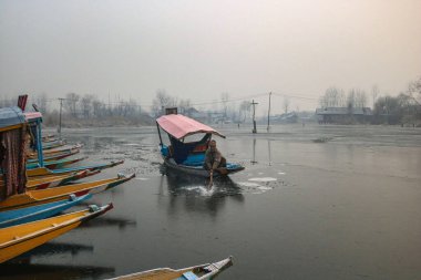 SRINAGAR INDIA 21 ARALIK 2024 Bir kayıkçı 21 Aralık 2024 'te Srinagar Hindistan' da Dal Gölü 'nün donmuş yüzey kısımlarını kırar. Kaşmir soğuk bir dalganın pençesinde ve Chillai Kalan' ın 40 günlük dönemi soğuk bir espriyle Vadi 'de başladı.