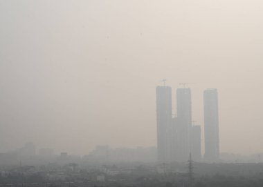 26 Aralık 2024 Noida Hindistan 'da 26 Aralık 2024 günü öğleden sonra yükselen hava kirliliği ve sisli hava nedeniyle gökdelenlerin görüntüsü sisli bir hava dalgası Hindistan' ı vurdu.