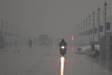 NEW DELHI INDIA DECEMBER 27 2024 Commuters out in cold and rainy weather morning at Kartavya Path near India Gate on December 27 2024 in New Delhi India Delhi and nearby areas received moderate to heavy rain on Friday leading to a drop in temperature clipart