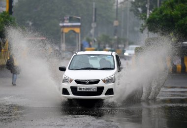 NOIDA INDIA 27 Aralık 2024 Noida Hindistan 'da 27 Aralık 2024 tarihinde yağmurdan dolayı 21A sektöründeki su dolu bir yoldan geçen banliyö sakinleri, Cuma günü Hindistan Meteorolo' sunun düşmesine yol açan hafif ve yoğun yağmurlu bölgelere ulaştı.