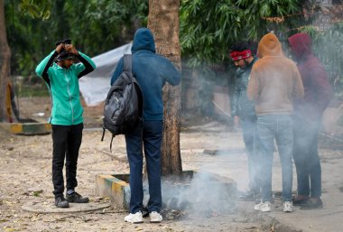 NOIDA INDIA DECEMBER 30 2024 People stood around bonfire near Sector 24 road to escape the cold Cold has increased in Delhi NCR mercury has gone down further morning temperature was 8 degree Celsius clipart