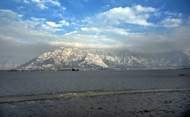 30 Aralık 2024 'te Hindistan' ın Srinagar kentinde kar dağları ve donmuş Dal Gölü 'nü gösteren genel bir bakış açısı vardır. Kaşmir 'e Cuma ve Cumartesi günü yoğun kar yağışı yağdı ve bu da vadinin bazı bölgelerinin kapatılmasına yol açtı. 