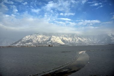30 Aralık 2024 'te Hindistan' ın Srinagar kentinde kar dağları ve donmuş Dal Gölü 'nü gösteren genel bir bakış açısı vardır. Kaşmir 'e Cuma ve Cumartesi günü yoğun kar yağışı yağdı ve bu da vadinin bazı bölgelerinin kapatılmasına yol açtı. 