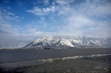 30 Aralık 2024 'te Hindistan' ın Srinagar kentinde kar dağları ve donmuş Dal Gölü 'nü gösteren genel bir bakış açısı vardır. Kaşmir 'e Cuma ve Cumartesi günü yoğun kar yağışı yağdı ve bu da vadinin bazı bölgelerinin kapatılmasına yol açtı. 