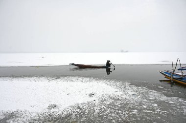 SRINAGAR, INDIA: 2 Ocak 2025 - Bir adam, Waseem Andrabi Hindustan Times tarafından Srinagar Hindistan 'da 2 Ocak 2025 tarihinde yapılan bir kar büyüsünün ardından Dal Gölü' nün donmuş yüzeyinde kürek çekiyor.. 