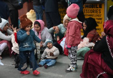 NEW DELHI INDIA JANUARY 4 2025 Passengers sit on a platform covering themselves with woolen cloths at New Delhi Railway Station several train services are impacted due to dense fog on January 4 2025 in New Delhi India A dense blanket of fog once agai clipart