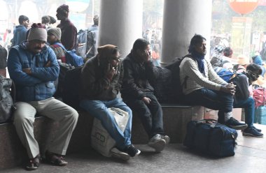 NEW DELHI INDIA 4 JANUARY 4. 2025 Yolcular, Yeni Delhi Tren İstasyonu 'nda kendilerini yünlü kumaşlarla örten bir platformda oturuyorlar 4 Ocak 2025' te yoğun sis nedeniyle yoğun tren seferleri bir zamanlar agai yoğun bir sis örtüsü altında kalmıştır.