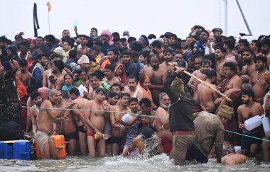 PRAYAGRAJ INDIA 14 HAZİRAN 2025 Bir polis 14 Ocak 2025 tarihinde Hindistan Prayagraj 'da Maha Kumbh Mela sırasında Makar Sakranti vesilesiyle Sangam' daki Shahi hamamı sırasında kalabalığı kontrol etmeye çalışıyor 