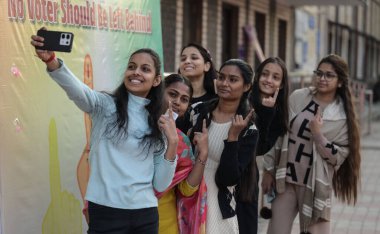 5 Şubat 2025 'te Yeni Delhi' de Rajkiya Sarvoda BAL Vidyalay Batı Vinod Nagar 'da yapılan Delhi Meclis Seçimleri sırasında oy kullanma merkezinde fotoğraf çeken genç seçmenler 