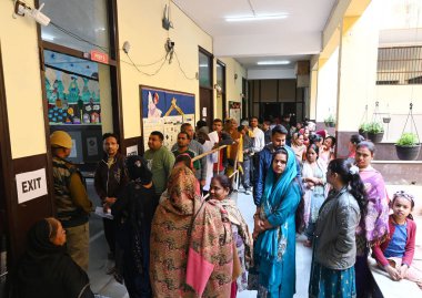 NEW DELHI, INDIA: 5 Şubat 2025 - İnsanlar, 5 Şubat 2025 tarihinde Yeni Delhi 'de Goyla Dairy' deki bir kabin merkezinde oy kullanmak için sırada bekliyorlar.. 